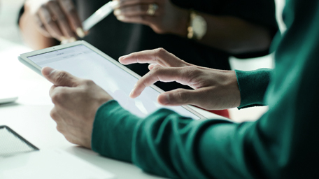 Close-up of co-workers standing at desk with laptop and talking