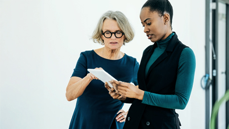 Two women reading news articles from phone.