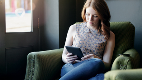 Woman reading ebook on tablet in coffee shop