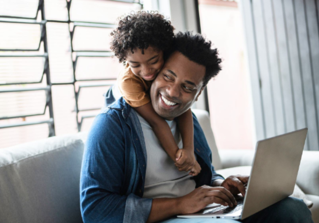 man-on-laptop-with-child-cuddling-over-shoulders